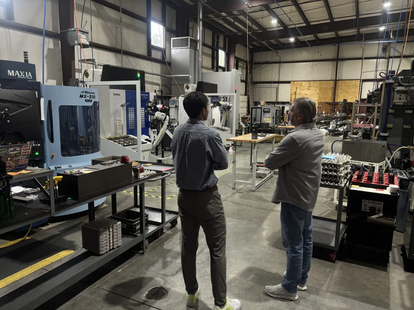 A Structify team member and a shop owner looking over a floor of CNC machining centers