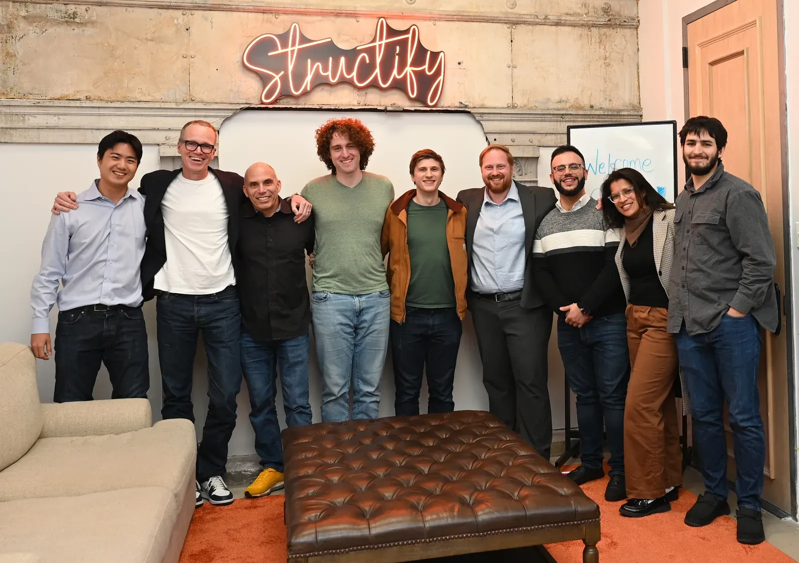 The Structify team together under the Structify sign in the New York office